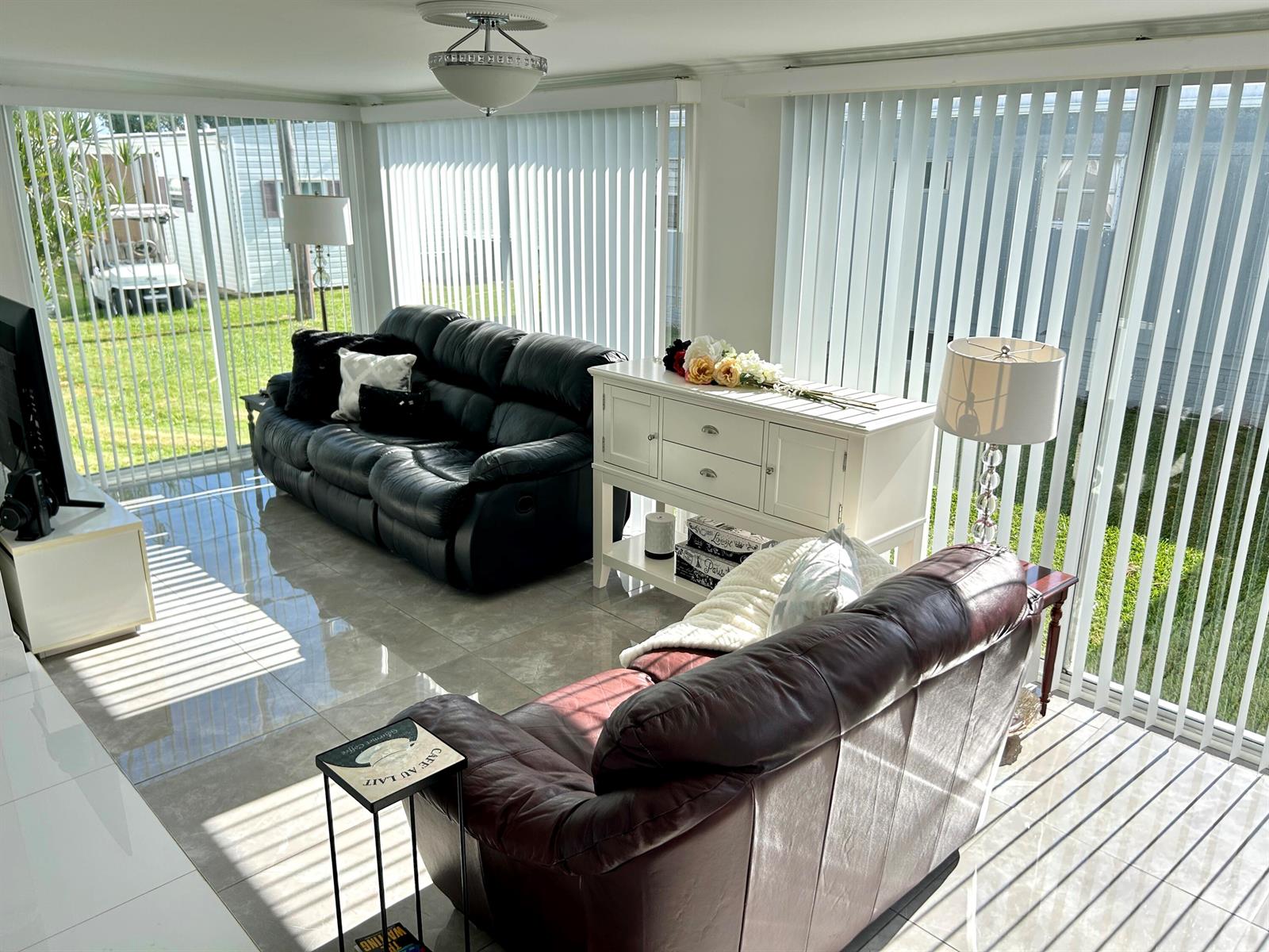 A sunroom features tile flooring, two leather sofas, a white sideboard, and floor-to-ceiling vertical blinds — 3233 State Street, Hollywood FL 33021, HOLLYWOOD, FL