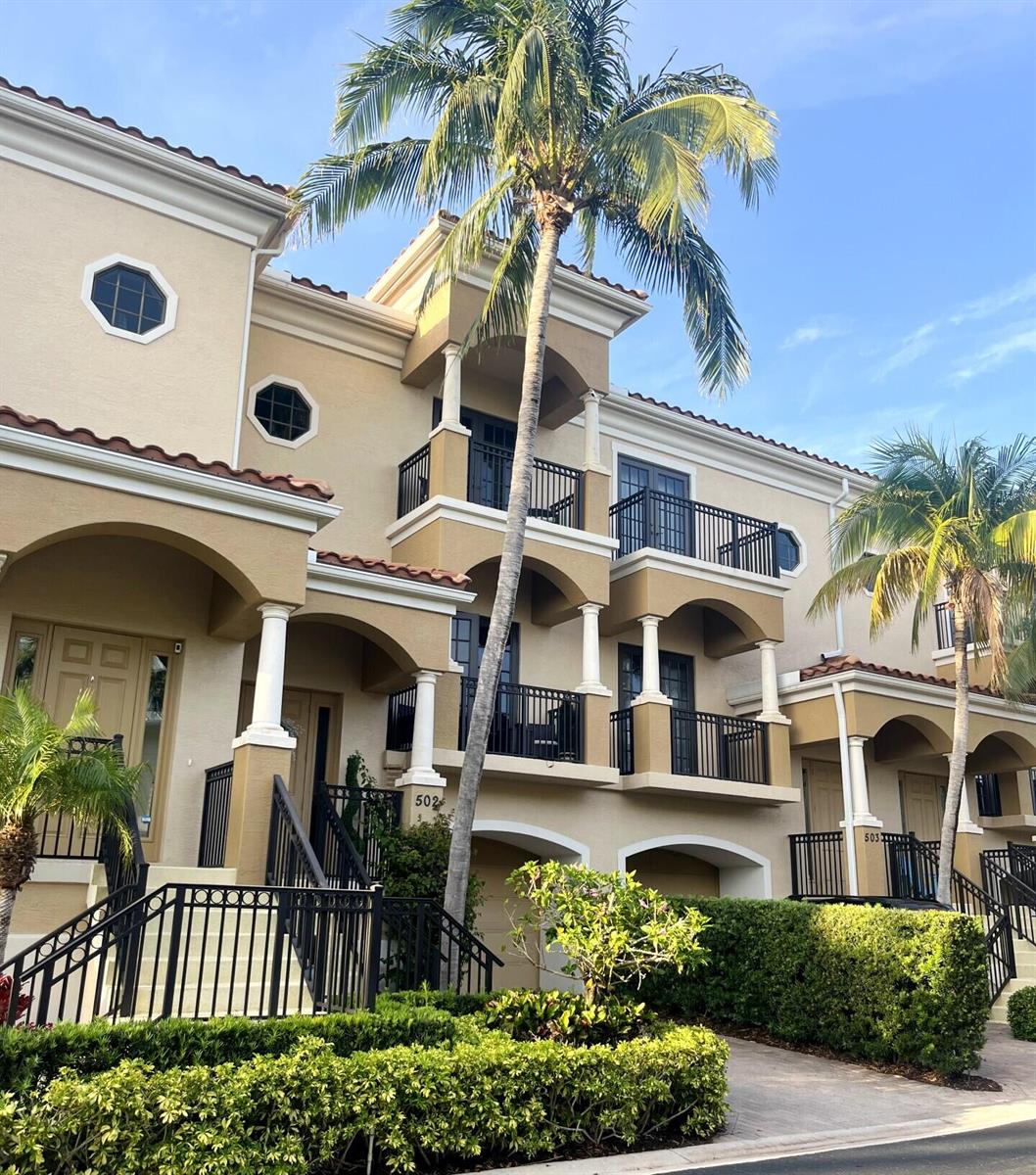 A multi-story tan townhouse complex features arched entryways, black metal railings, and palm trees — 502 Del Sol Circle, Tequesta FL 33469, TEQUESTA, FL