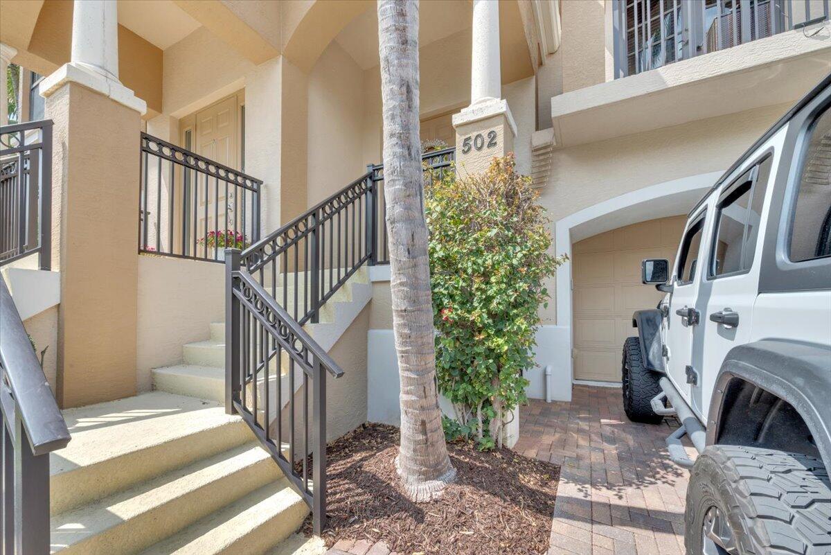 A tan building exterior features a staircase with black railings and a parked white Jeep — 502 Del Sol Circle, Tequesta FL 33469, TEQUESTA, FL