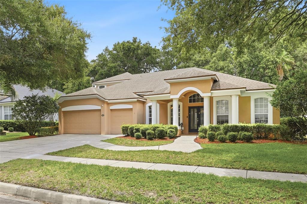 A single-story tan house with a three-car garage and a columned entryway — 483 WEKIVA PRESERVE DRIVE, APOPKA, FL