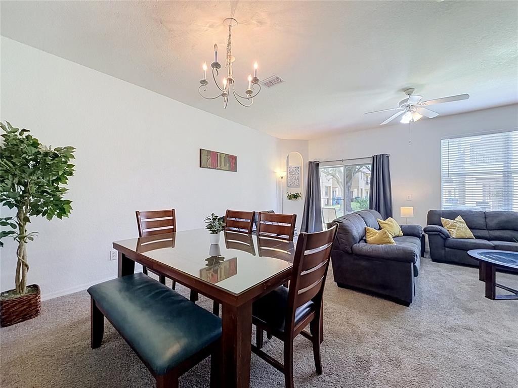 A dining area with a glass-topped table and chairs opens into a carpeted living room — 220 TERRA LAGO STREET, DAVENPORT, FL