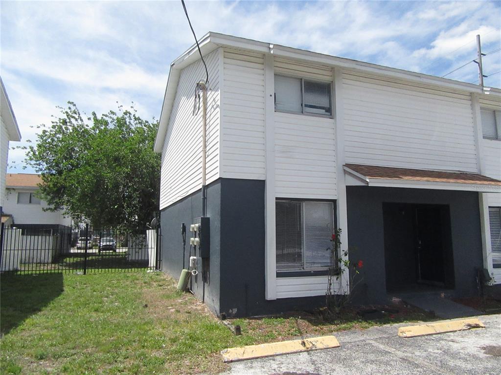 A two-story townhouse exterior with white siding, dark gray lower walls, and a paved parking area — 13050 N 20TH STREET, TAMPA, FL