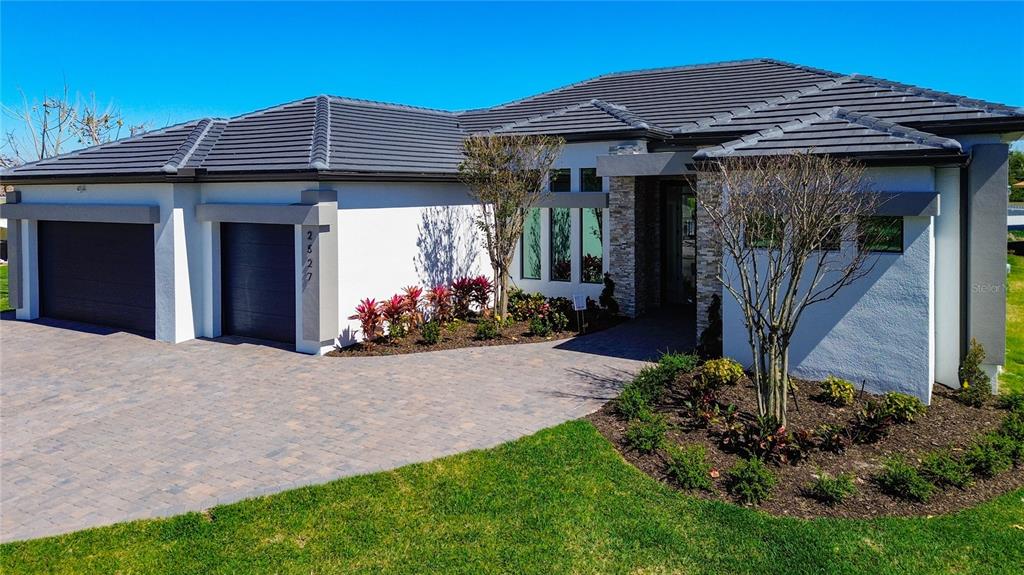 A modern single-story house with a paved driveway, two-car garage, and stone-accented entryway — 2527 GLEASON PARKWAY, CAPE CORAL, FL