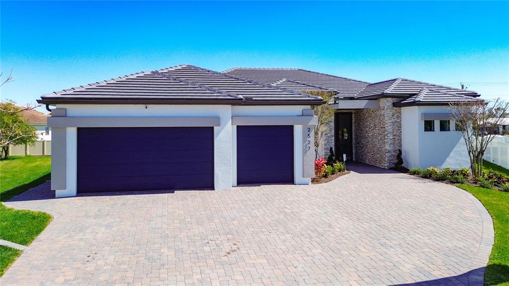 A single-story house with a two-car garage, stone facade, and a paved driveway — 2527 GLEASON PARKWAY, CAPE CORAL, FL