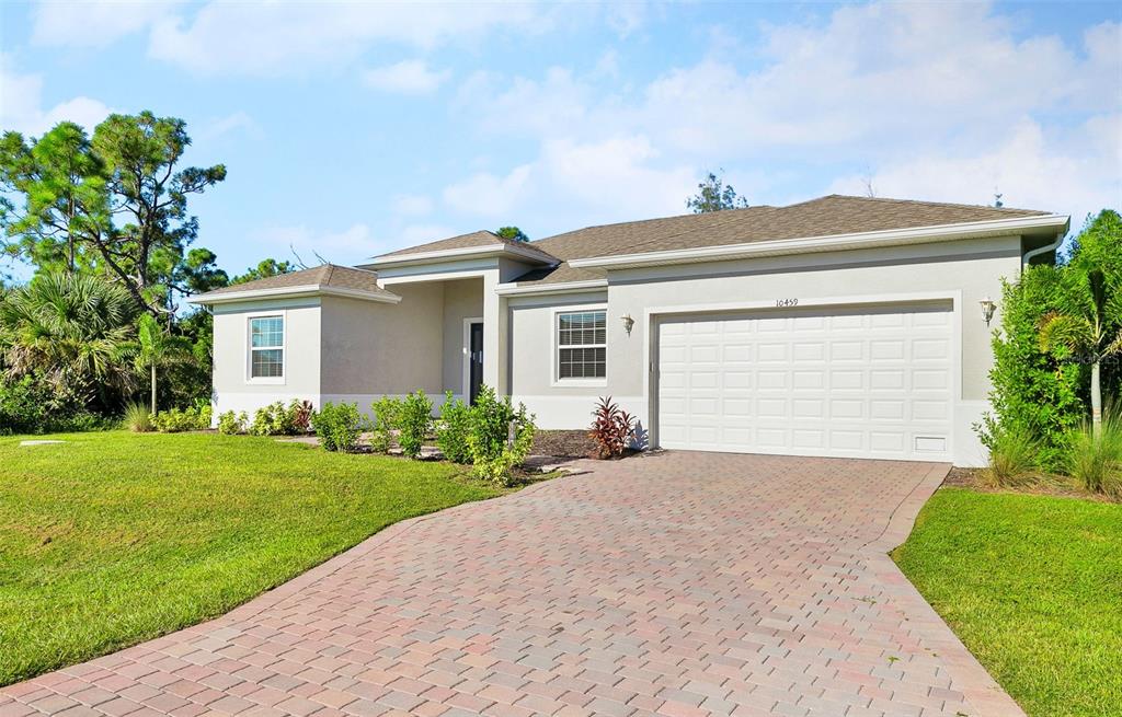 A single-story house with a paved driveway, a two-car garage, and a landscaped front yard — 10459 LIVE OAK ROAD, PORT CHARLOTTE, FL