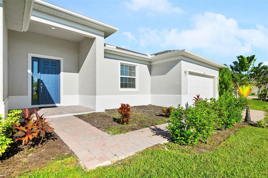 A single-story house with a blue front door, a brick walkway, and a two-car garage — 10459 LIVE OAK ROAD, PORT CHARLOTTE, FL