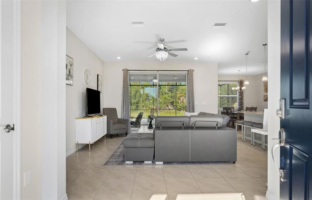 A view from an entryway into a living room with tile floors and a gray sofa — 10459 LIVE OAK ROAD, PORT CHARLOTTE, FL