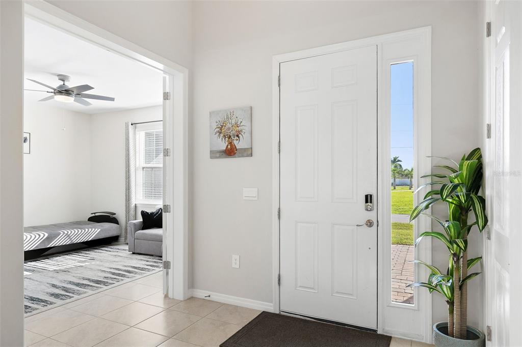 A bright entryway features tile flooring, a white front door, and a view into a bedroom — 10459 LIVE OAK ROAD, PORT CHARLOTTE, FL