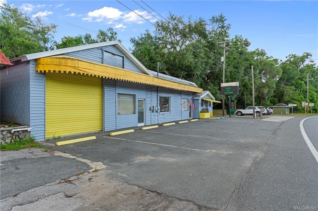 A blue commercial building with a yellow roll-up door and awning sits by a road — 7805 S FLORIDA AVENUE, FLORAL CITY, FL