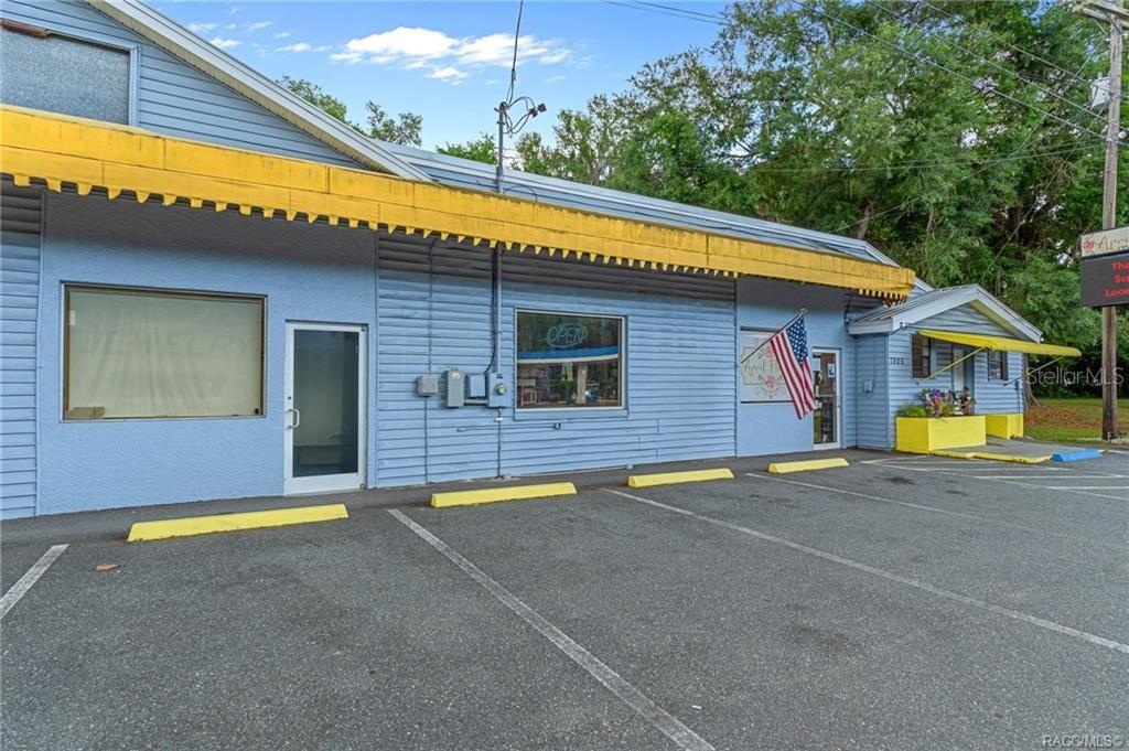 A light blue commercial building with a yellow awning and a parking lot in front — 7805 S FLORIDA AVENUE, FLORAL CITY, FL