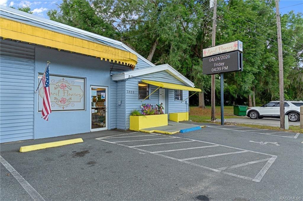 A light blue commercial building with yellow awnings and a parking lot in front — 7805 S FLORIDA AVENUE, FLORAL CITY, FL