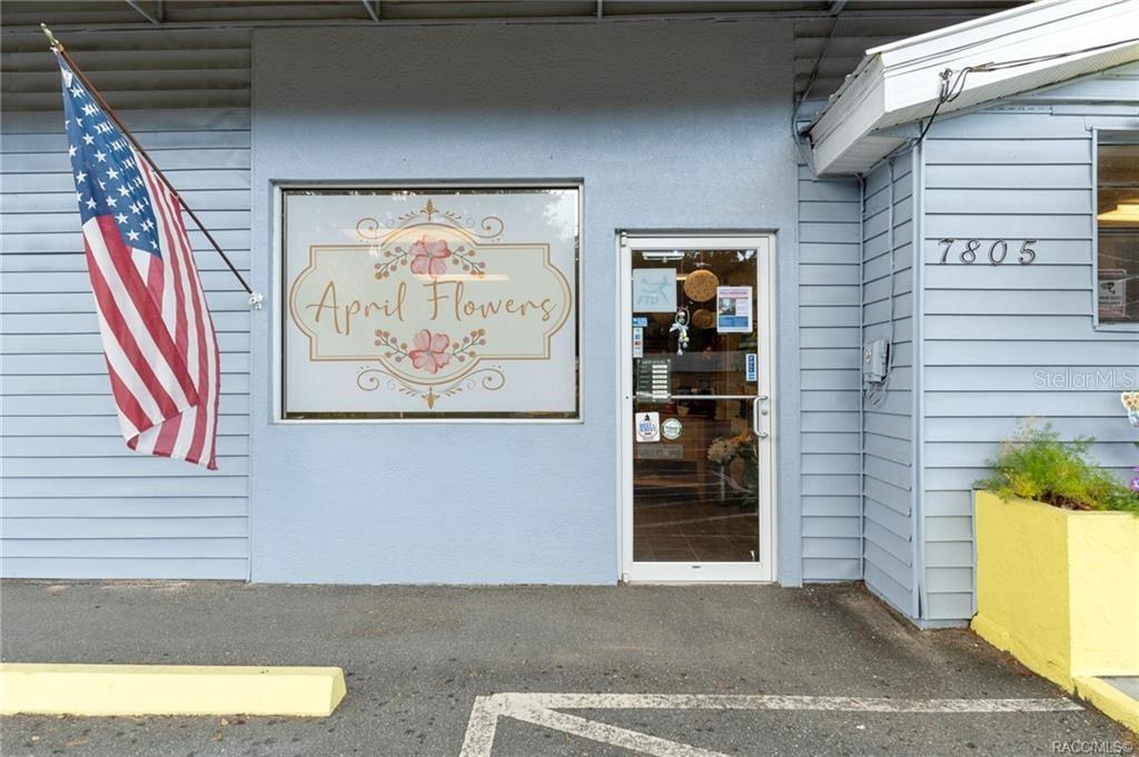 The exterior of a light blue building features a flower shop sign and an American flag — 7805 S FLORIDA AVENUE, FLORAL CITY, FL