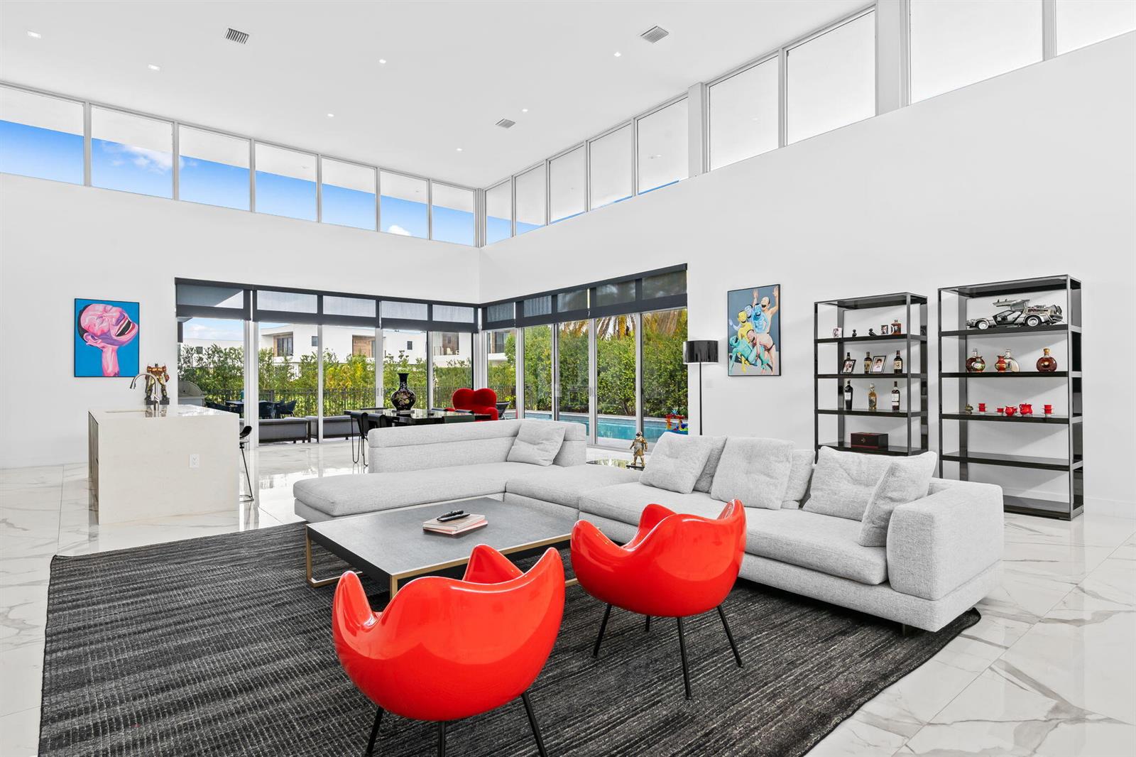 A modern living room features a large sectional sofa, two red chairs, and floor-to-ceiling windows — 16758 Natures Way, Weston FL 33326, WESTON, FL