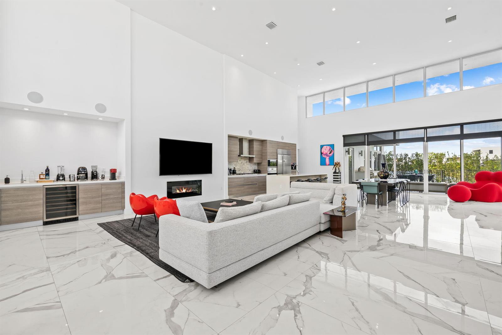 A spacious, modern living room features white marble floors, high ceilings, and a fireplace — 16758 Natures Way, Weston FL 33326, WESTON, FL