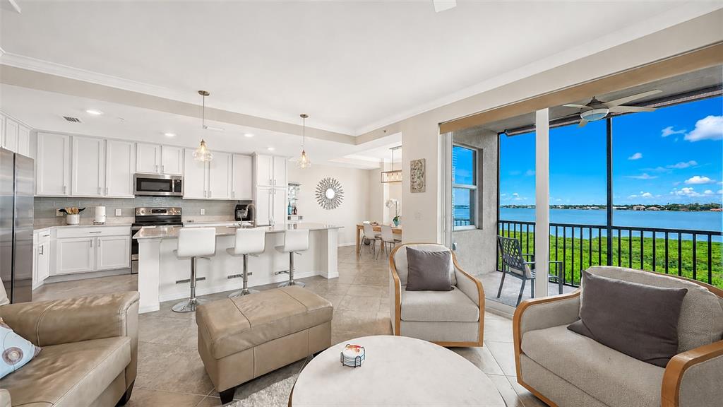 An open-concept kitchen and living area features white cabinetry, a breakfast bar, and balcony views — 1020 TIDEWATER SHORES LOOP UNIT 207, BRADENTON, FL