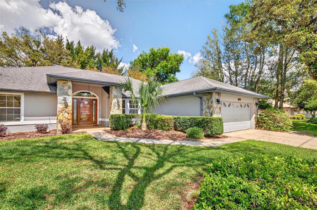 A single-story house with a stone-accented entryway, a two-car garage, and a landscaped front yard — 5393 SW 86TH PLACE, OCALA, FL