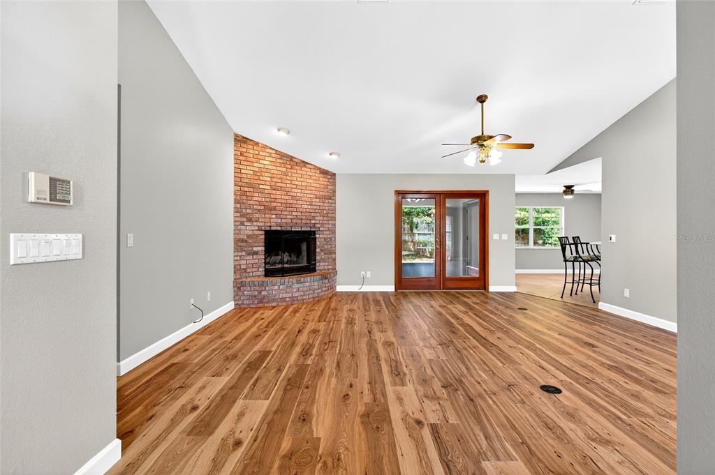 A living room features wood flooring, a brick corner fireplace, and double glass doors — 5393 SW 86TH PLACE, OCALA, FL
