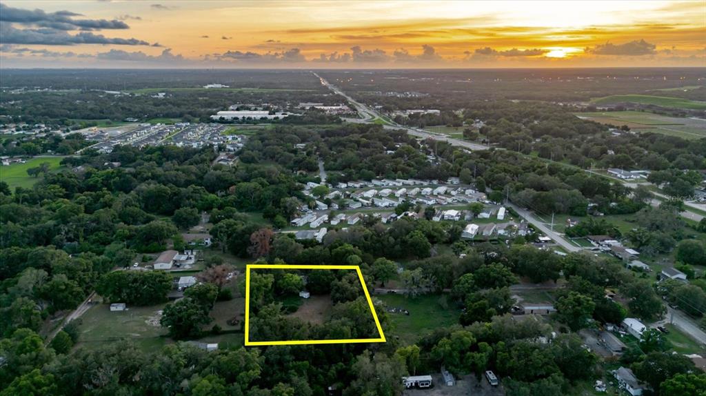 An aerial view shows a rectangular lot outlined in yellow amidst a wooded residential area — 11152 GALAXY LANE, THONOTOSASSA, FL