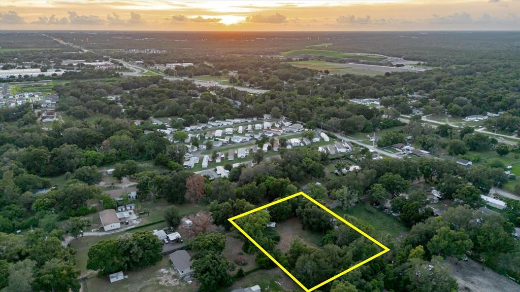 An aerial view shows a rectangular plot of land outlined in yellow amidst wooded surroundings — 11152 GALAXY LANE, THONOTOSASSA, FL