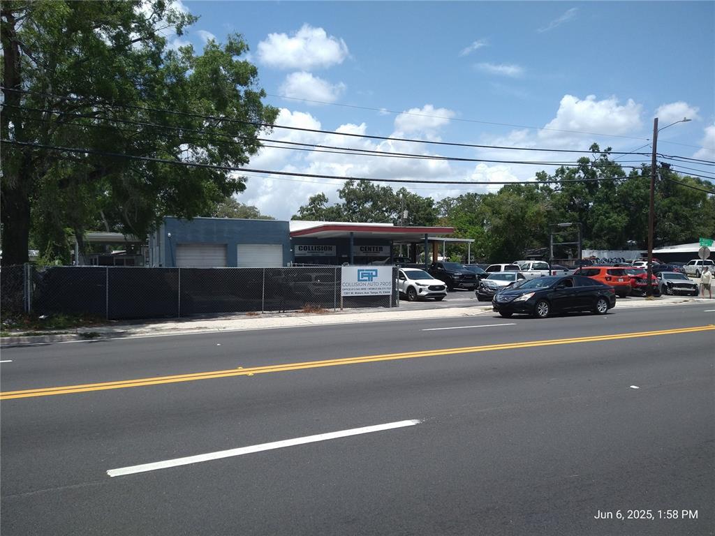 A street-level view of a collision center with a parking lot and chain-link fence — 1301 W WATERS AVENUE, TAMPA, FL