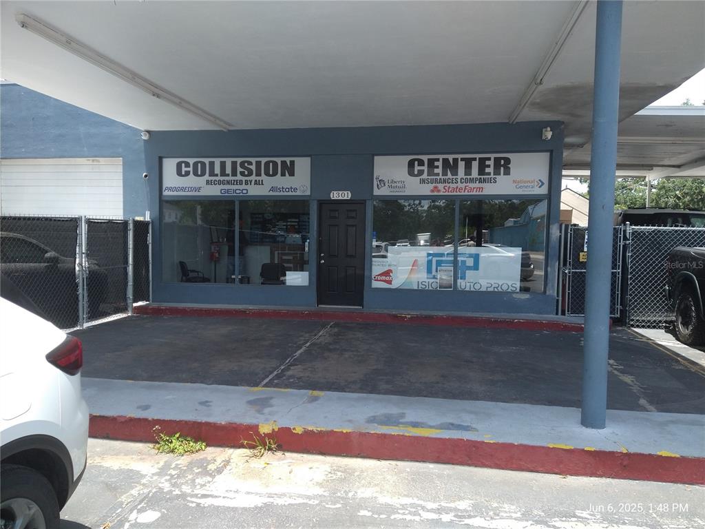 The exterior of a commercial collision center building features a covered parking area and signage — 1301 W WATERS AVENUE, TAMPA, FL