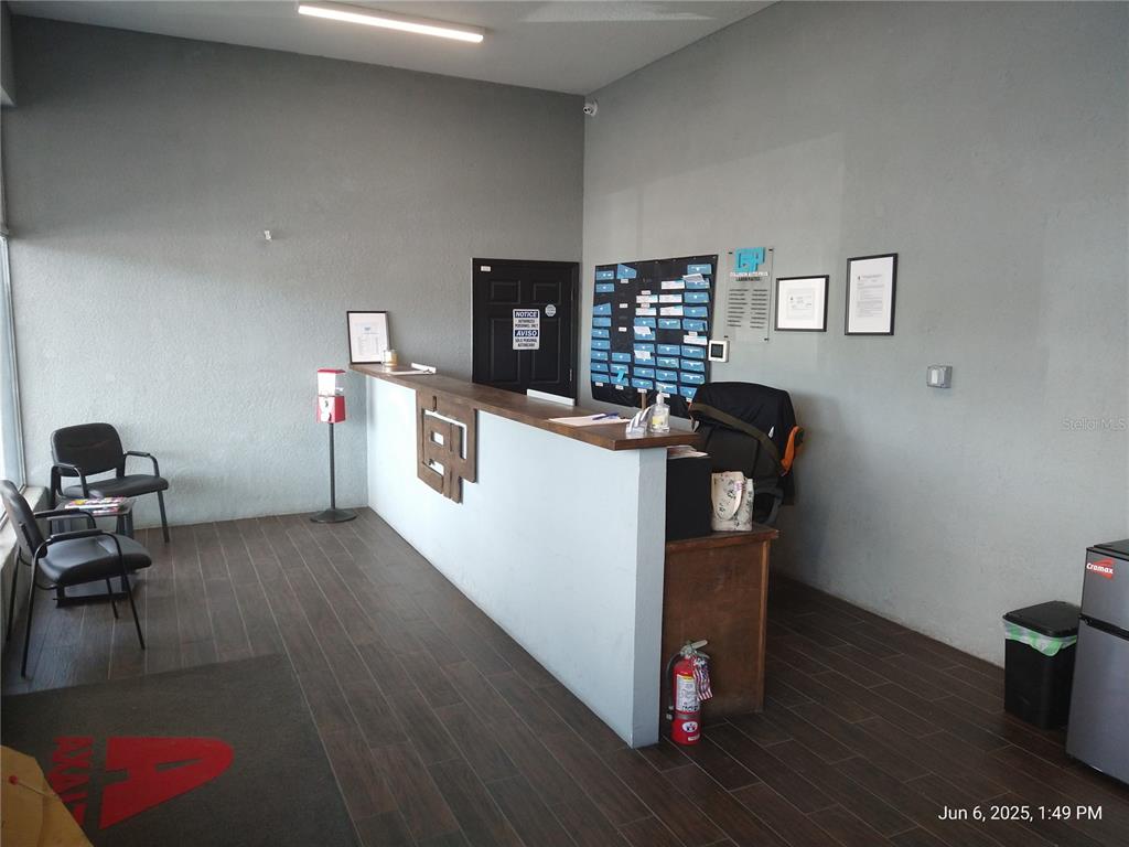 A reception area features a wooden desk, dark wood-look flooring, and gray walls — 1301 W WATERS AVENUE, TAMPA, FL