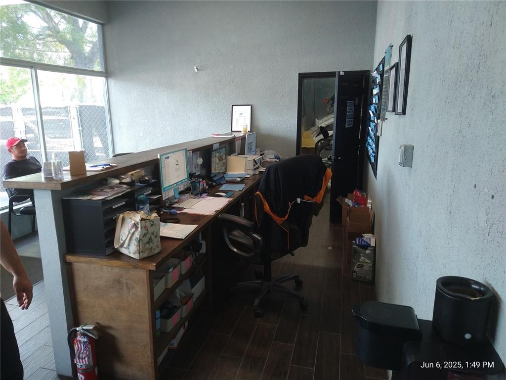 A reception area features a wooden desk, office chair, and large windows overlooking an outdoor area — 1301 W WATERS AVENUE, TAMPA, FL