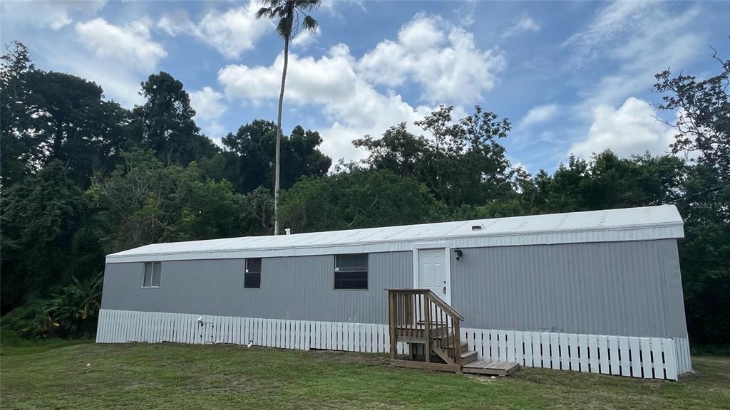 A grey mobile home with a white metal roof and a small wooden front staircase — 9860 GOLDEN LOOP, NEW PORT RICHEY, FL