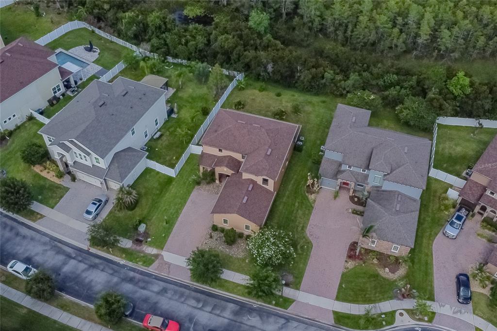 An aerial view shows three suburban houses with driveways and backyards bordering a wooded area — 3280 SOMERSET PARK DRIVE, ORLANDO, FL