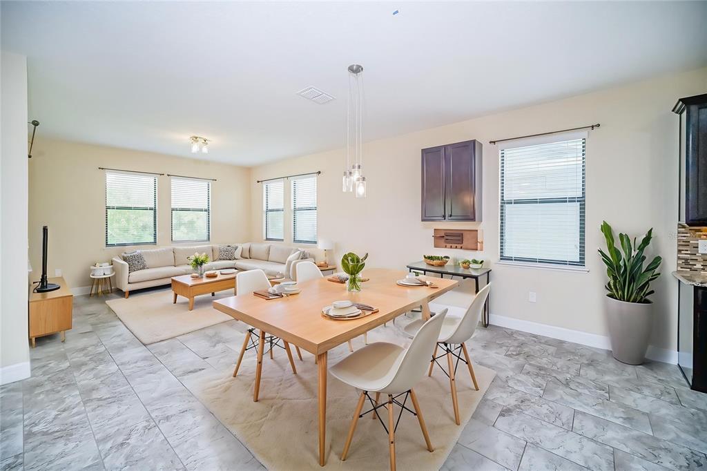 An open-concept living and dining area features light tile flooring, a wooden table, and neutral furniture — 3280 SOMERSET PARK DRIVE, ORLANDO, FL
