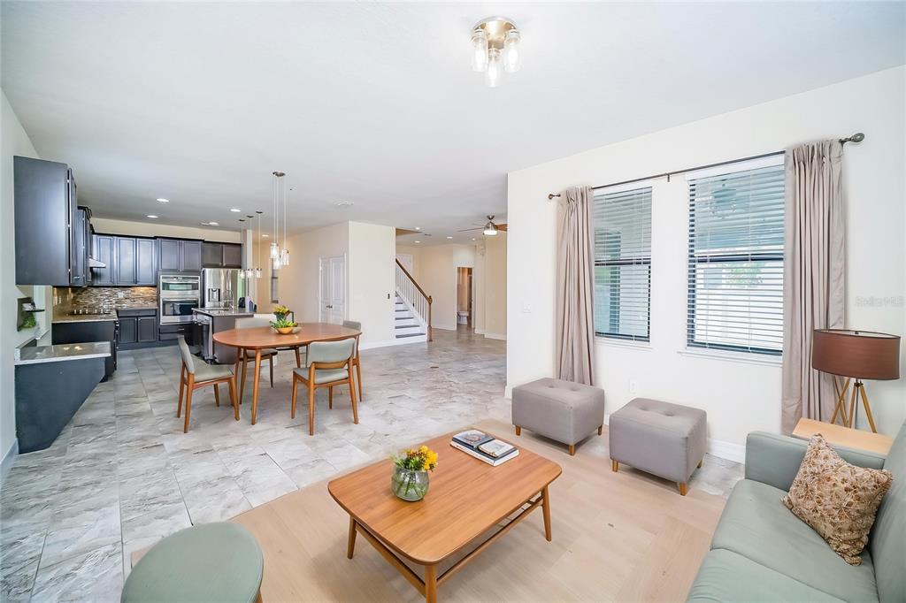 An open-concept living room and kitchen featuring tile and wood flooring, dark cabinetry, and furniture — 3280 SOMERSET PARK DRIVE, ORLANDO, FL