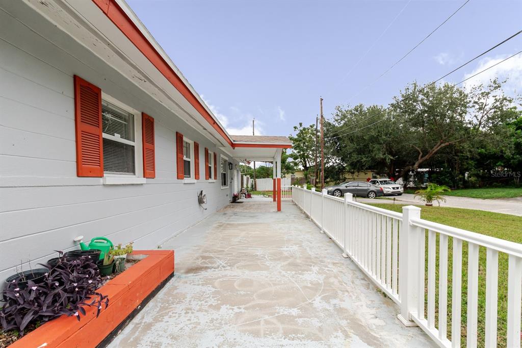 A concrete patio with a white railing runs alongside a house with orange shutters — 7200 8TH STREET N, ST PETERSBURG, FL