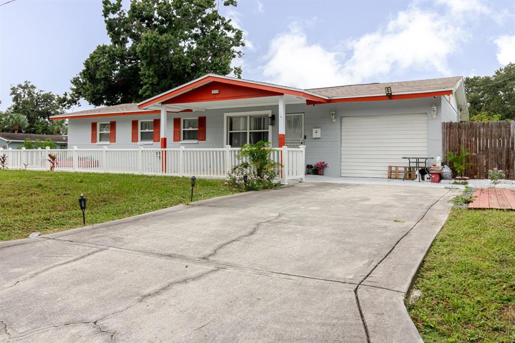 A single-story house with gray siding, orange trim, a white fence, and a concrete driveway — 7200 8TH STREET N, ST PETERSBURG, FL