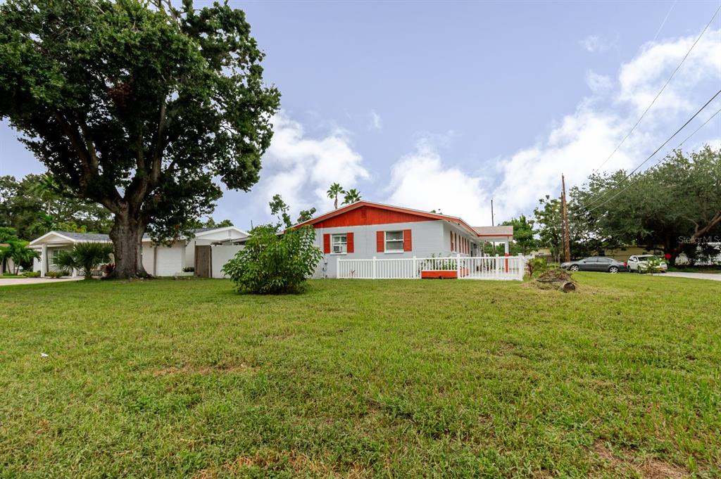 A single-story house with a white fence and a large tree in the front yard — 7200 8TH STREET N, ST PETERSBURG, FL