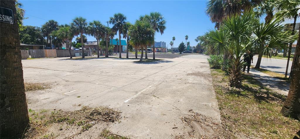 A large, flat concrete lot features several palm trees and a view of nearby buildings — E INTERNATIONAL SPEEDWAY BOULEVARD, DAYTONA BEACH, FL