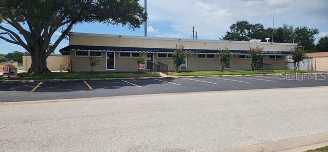 A single-story commercial building with a dark awning and a large tree in front — 6961 1ST AVENUE N, ST PETERSBURG, FL