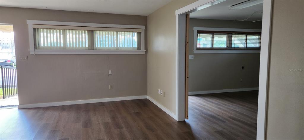 An interior view shows two connected rooms with wood-look flooring and horizontal windows — 6961 1ST AVENUE N, ST PETERSBURG, FL