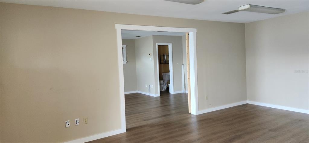 An interior view shows a room with beige walls, wood-look flooring, and a wide doorway — 6961 1ST AVENUE N, ST PETERSBURG, FL