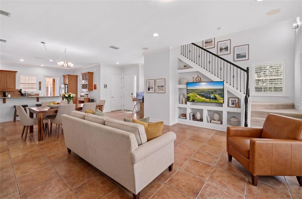 An open-concept living and dining area features tile flooring, a built-in media center, and stairs — 7526 EXCITEMENT DRIVE, REUNION, FL