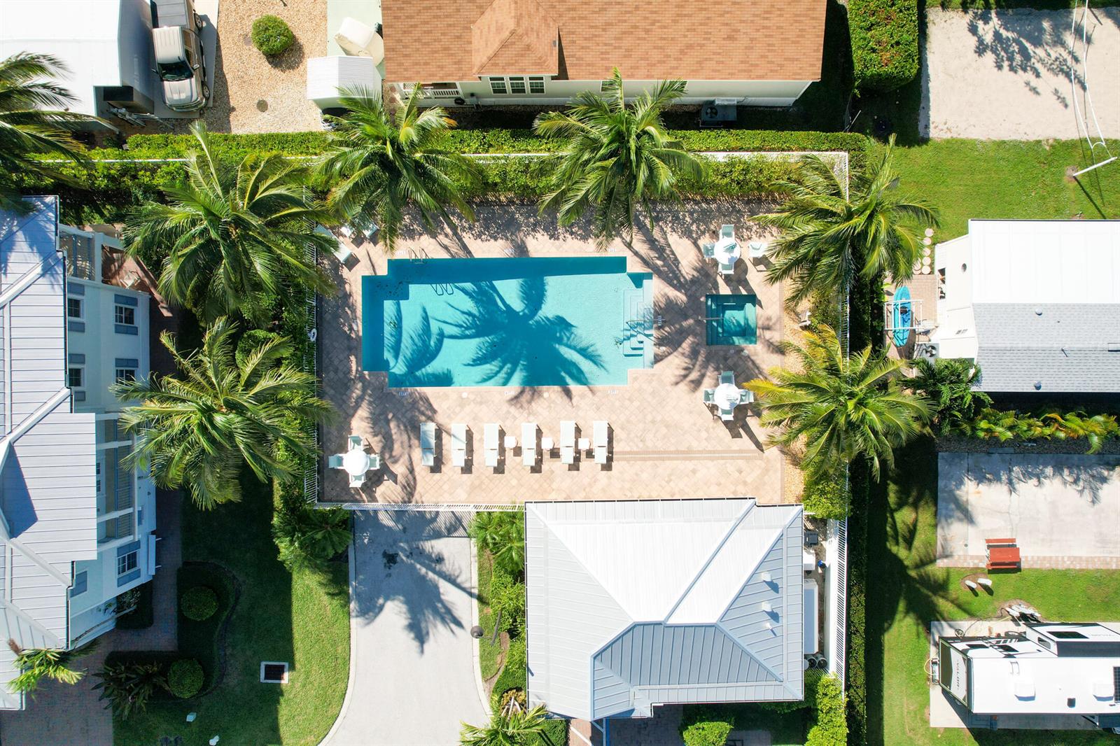 An aerial view shows a swimming pool and hot tub surrounded by lounge chairs and palm trees — 144 Ocean Breeze Drive, Juno Beach FL 33408, JUNO BEACH, FL
