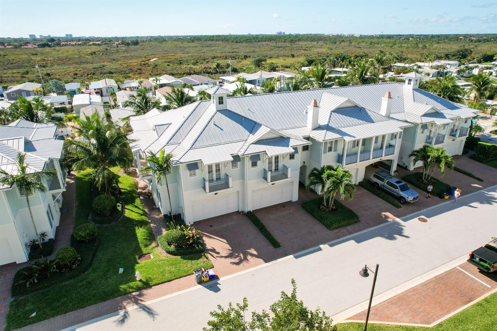 An aerial view of a multi-unit residential building with metal roofs and brick driveways — 144 Ocean Breeze Drive, Juno Beach FL 33408, JUNO BEACH, FL
