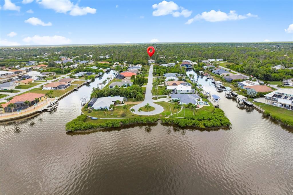 An aerial view shows waterfront houses along canals leading to a large body of water — 13353 GORMAN AVENUE, PORT CHARLOTTE, FL