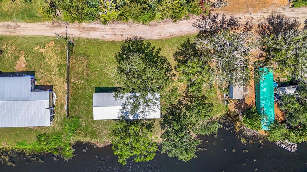 An aerial view shows a house with a metal roof situated on a waterfront lot — 3380 MAPLE LANE, HAINES CITY, FL