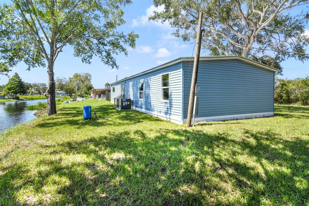 The exterior of a blue manufactured home sits on a grassy lot beside a canal — 3380 MAPLE LANE, HAINES CITY, FL