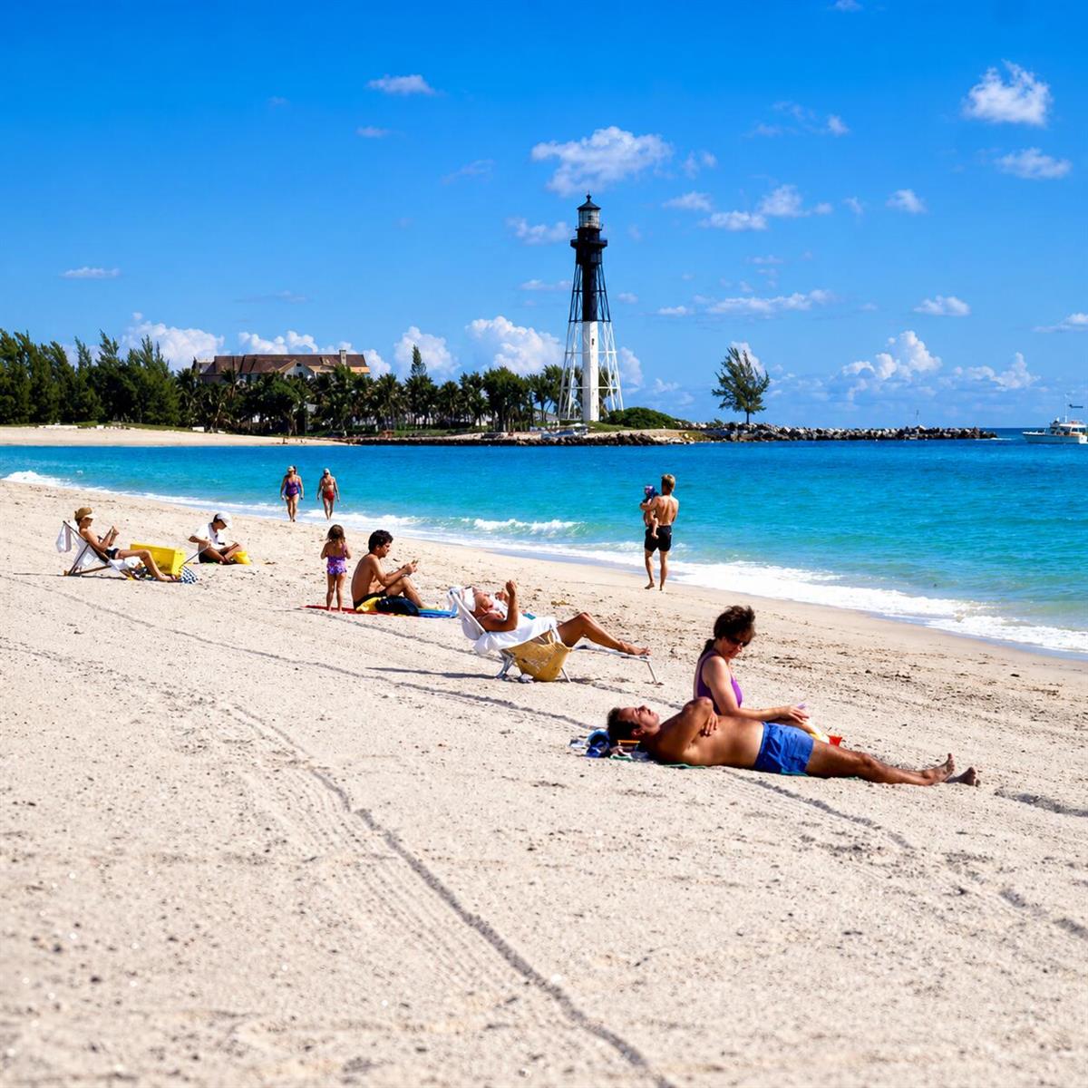 A sandy beach with people sunbathing near the water and a lighthouse in the distance — 1505 N Riverside Drive # 1002, Pompano Beach FL 33062, POMPANO BEACH, FL