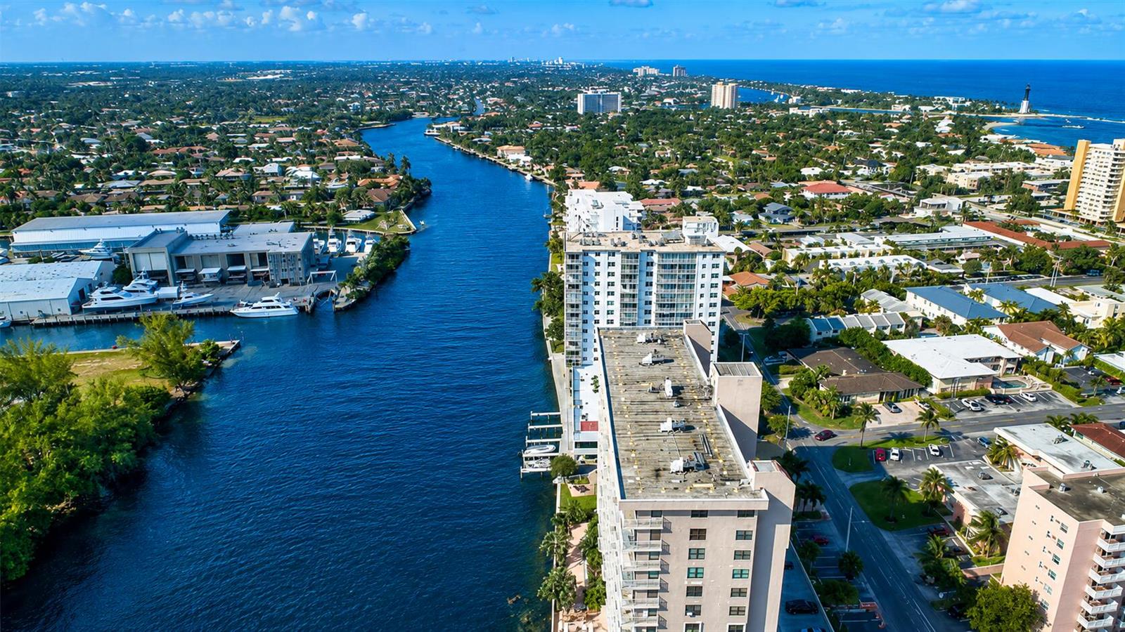 An aerial view shows a waterway lined with residential buildings, boats, and a coastal landscape — 1505 N Riverside Drive # 1002, Pompano Beach FL 33062, POMPANO BEACH, FL