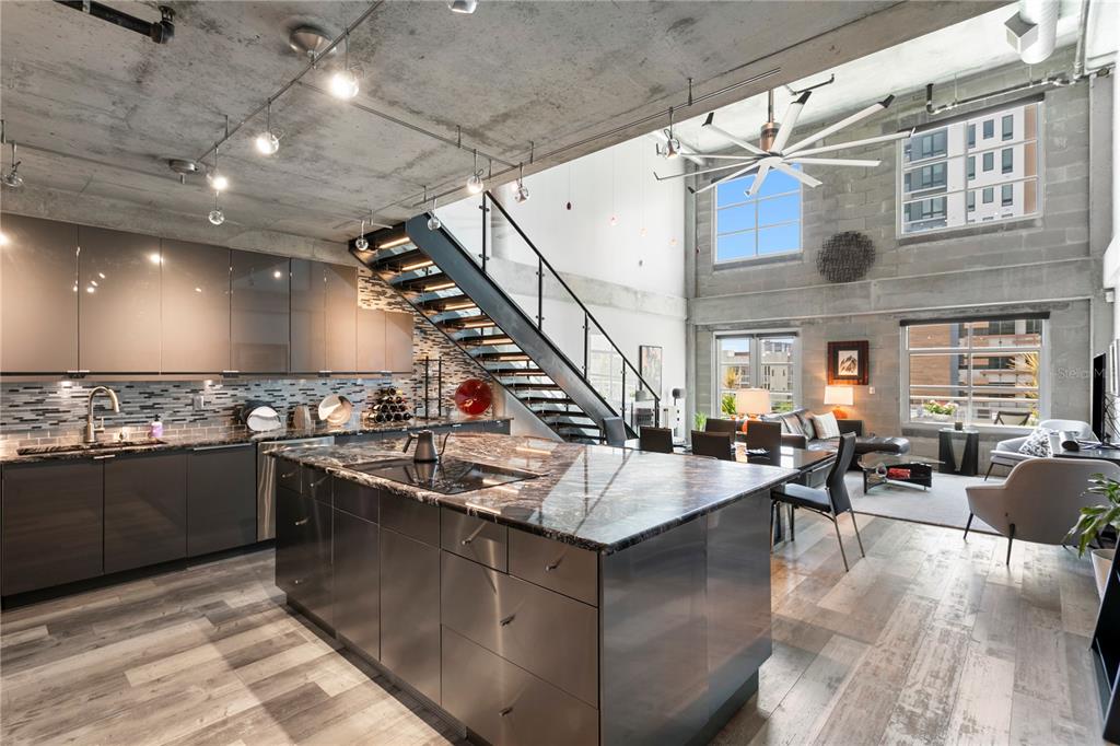 A modern open-concept kitchen and living area with concrete ceilings, metal stairs, and large windows — 1212 E WHITING STREET UNIT 404, TAMPA, FL