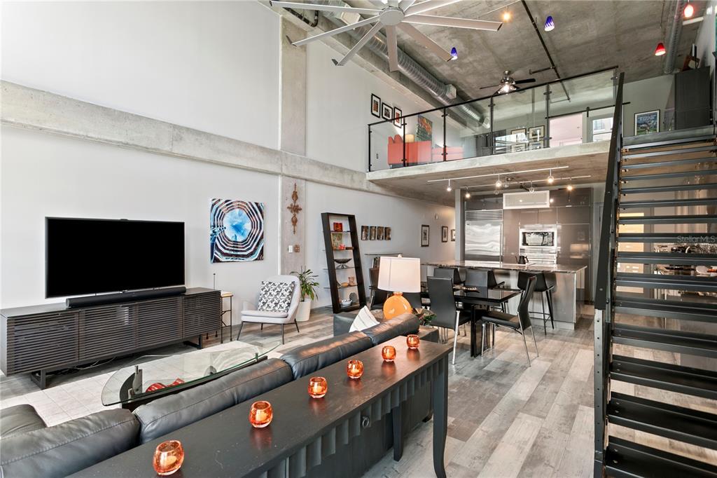 A modern open-concept living room and kitchen with high ceilings, concrete accents, and a staircase — 1212 E WHITING STREET UNIT 404, TAMPA, FL