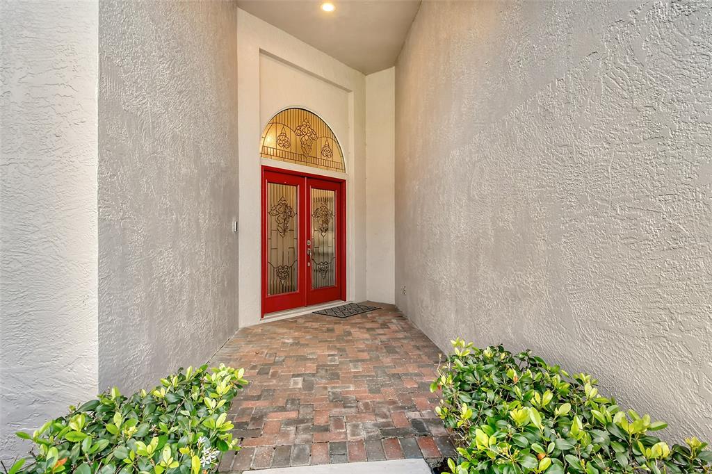 A brick walkway leads to a red double front door with a decorative arched transom window — 6738 PLEASANT HILL ROAD, BRADENTON, FL
