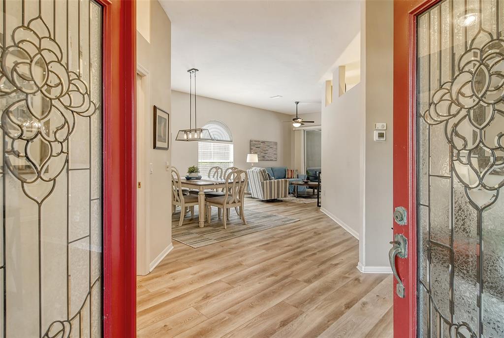 A view from an open front door into a dining area and living room with wood-look flooring — 6738 PLEASANT HILL ROAD, BRADENTON, FL